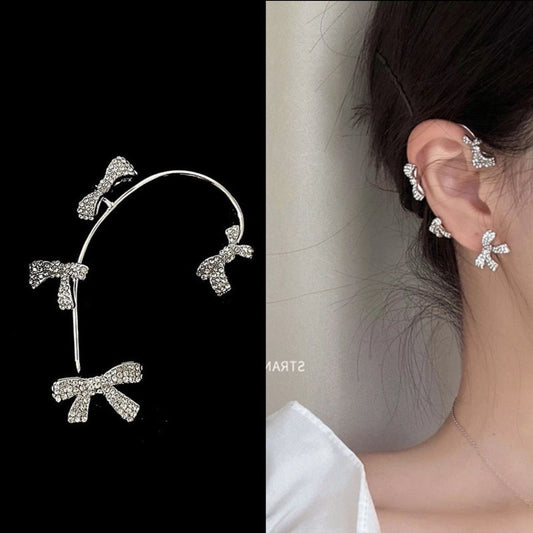 Turn heads with our dazzling Rhinestone Bow Ear Cuff Set – the ultimate blend of sweet charm and edgy glam. Featuring multiple sparkling crystal bows on a sleek silver-tone frame, this ear cuff hugs your ear with whimsical elegance. No piercing needed, just effortless style.